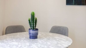 Uma mesa redonda de mármore com um vaso azul contendo um cacto verde.