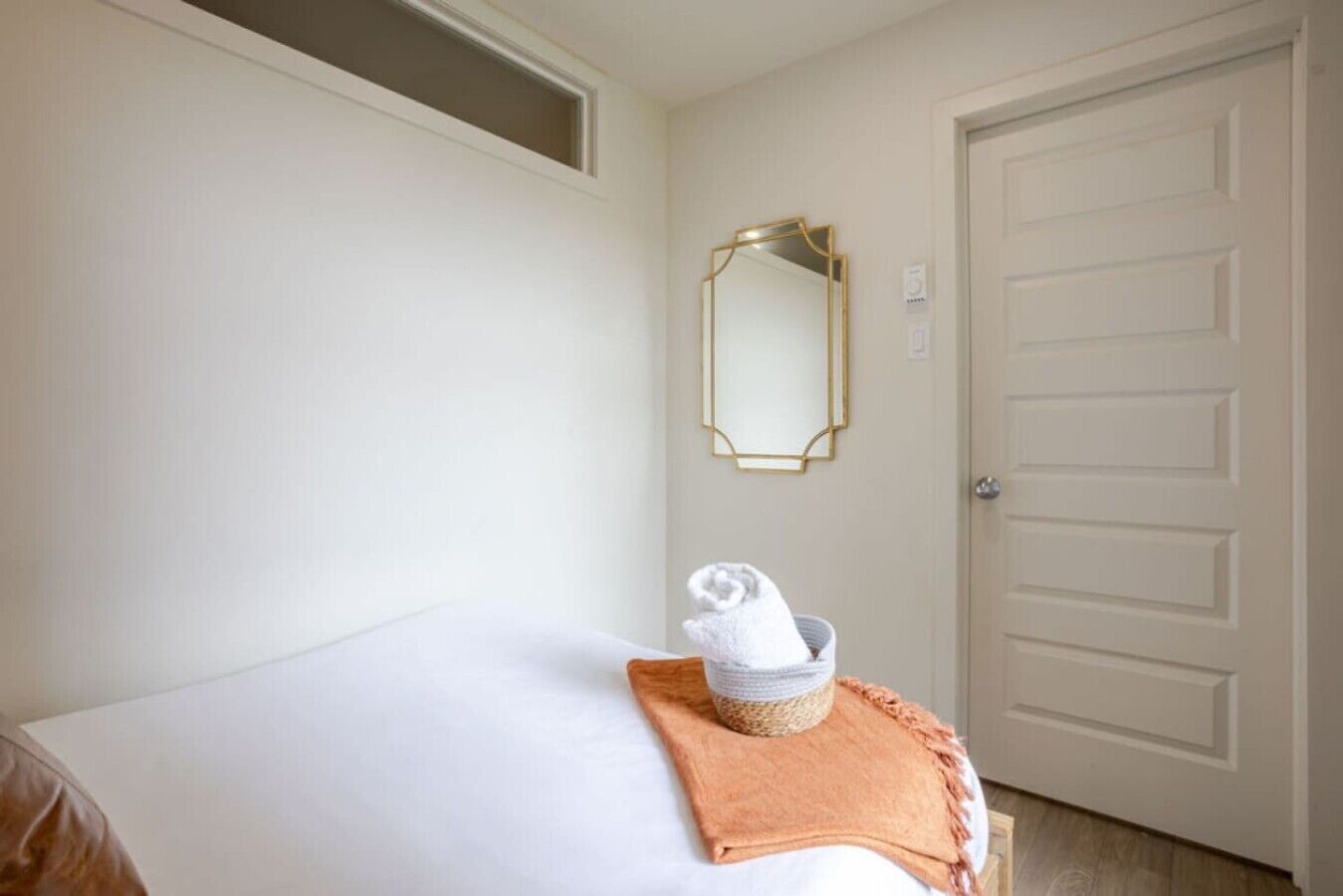 Una habitación de hotel con una cama, una puerta blanca y un espejo en la pared.