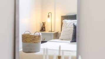 Un dormitori amb llit, taula de nit, làmpada i un mirall que reflecteix l'habitació.