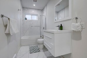 A modern bathroom with a shower, toilet, and vanity. - Cozy & Bright | Prime Location (Montreal)