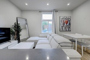 Una sala de estar moderna con un sofá, una televisión, una mesa de comedor y un cuadro en la pared.
