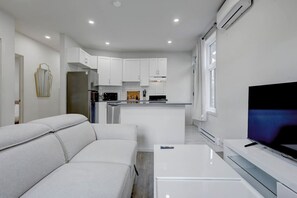 A modern kitchen with white cabinets, a built-in oven, and a refrigerator. - Cozy & Bright | Prime Location (Montreal)