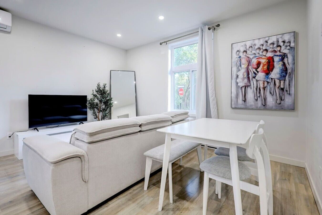 A modern living room with a sofa, TV, dining table, and chairs.