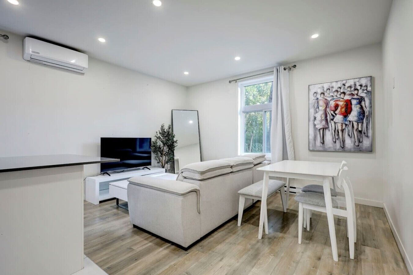 A modern living room with a flat-screen TV, a sofa, a dining table, and a window with curtains.