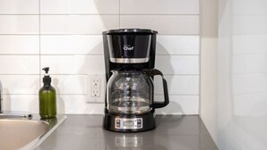 Eine schwarze Kaffeemaschine mit einer klaren Kanne auf einer Küchenarbeitsfläche.
