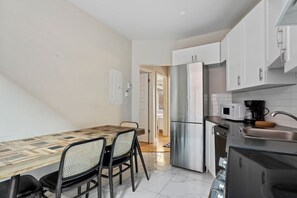 A compact kitchen with a dining table, chairs, a refrigerator, a microwave, and a sink.