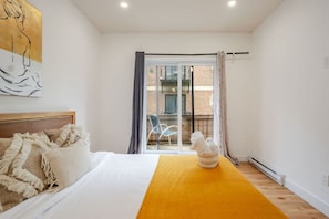 A bedroom with a bed, a yellow rug, a window with curtains, and a view of the outside. - Prime Downtown Spot | Easy Access (Montreal)