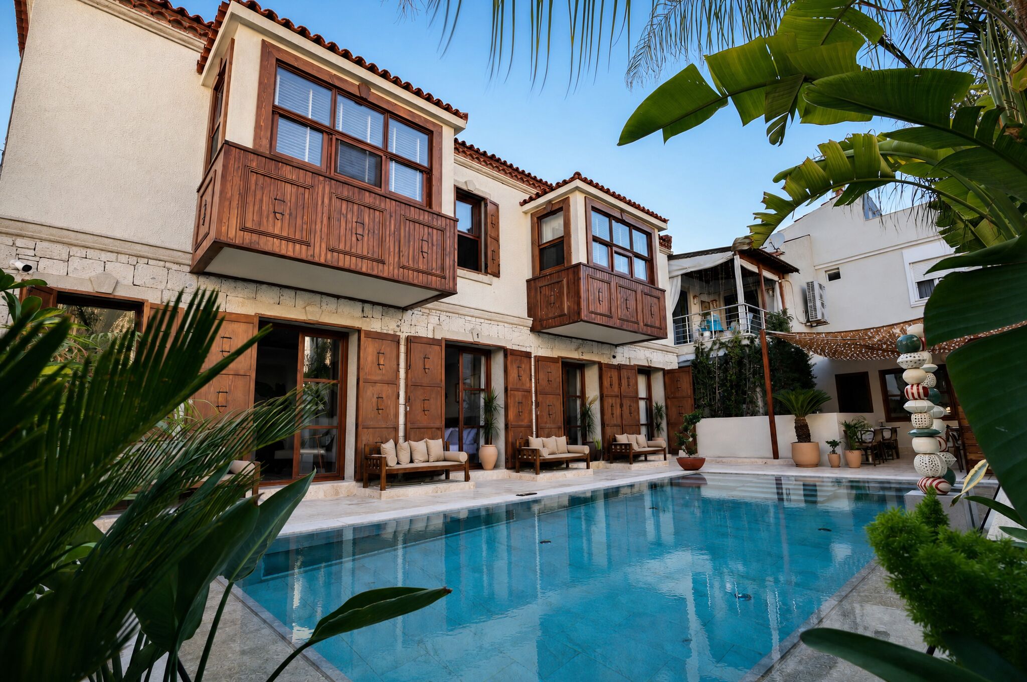 A two-story building with balconies, a swimming pool, and outdoor seating.