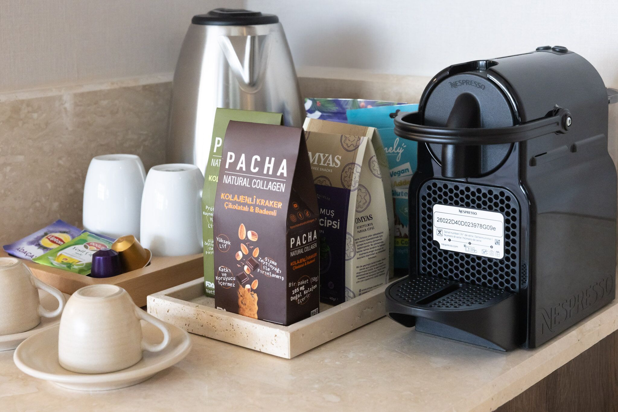 Un coin cuisine équipé d’une machine à café, de tasses à thé et de produits alimentaires emballés.