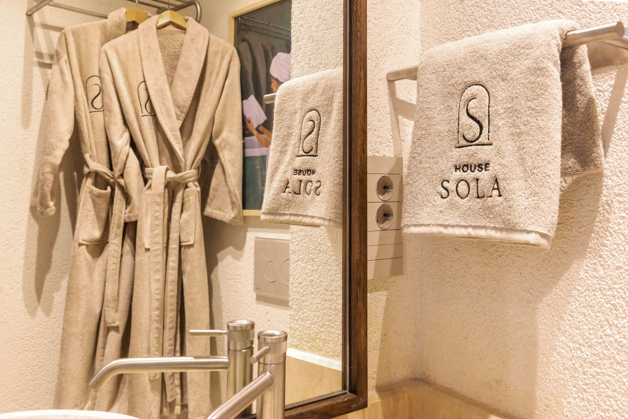 Ein Badezimmer mit Spiegel, Handtuchhalter und Handtüchern sowie einem an der Wand hängenden Bademantel.