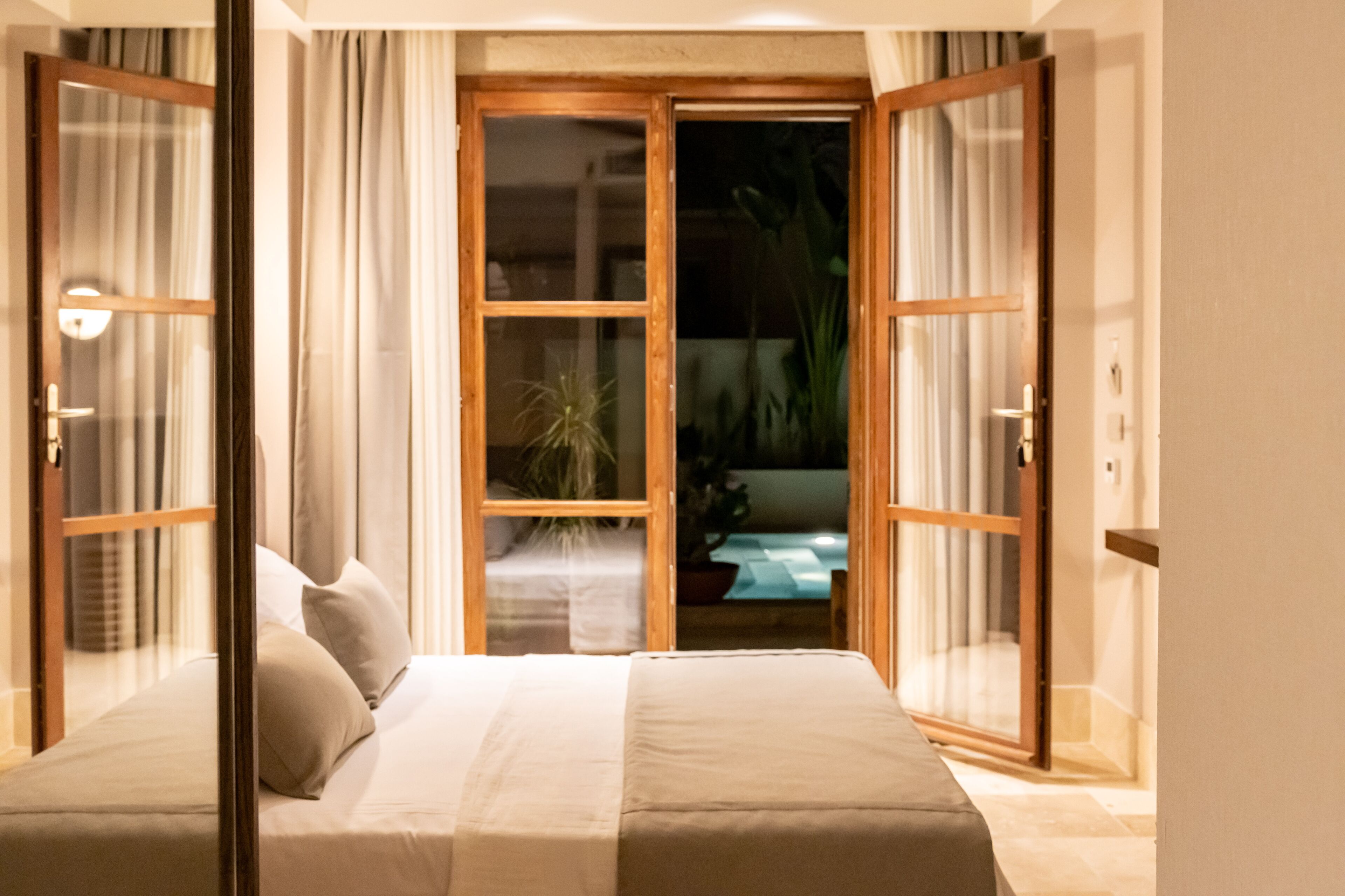 Una camera da letto con un letto, tende e vista panoramica attraverso una porta vetrata.