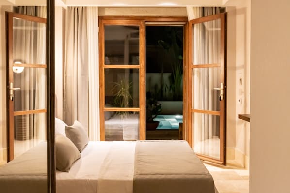 A bedroom with a bed, curtains, and a view through a glass door. - House Sola Alaçatı (Cesme)