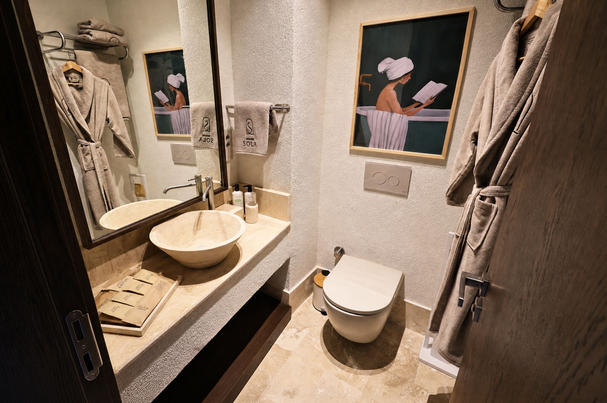 A bathroom with a sink, mirror, towel rack, toilet, and a framed picture on the wall.