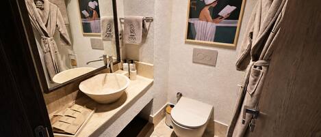 A bathroom with a sink, mirror, towel rack, toilet, and a framed picture on the wall.