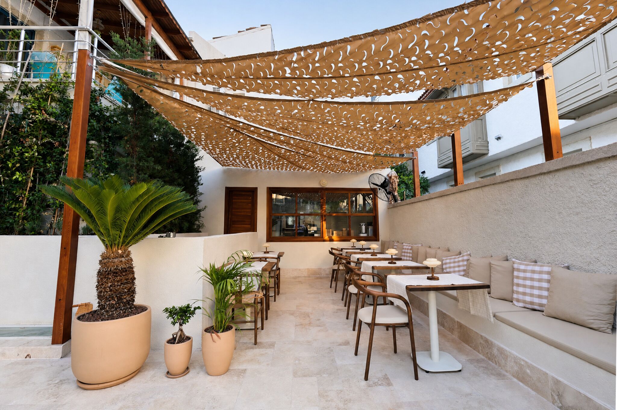 An outdoor patio area with tables and chairs, a sofa, and potted plants.