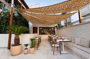 An outdoor patio area with tables and chairs, a sofa, and potted plants. - House Sola Alaçatı (Cesme)