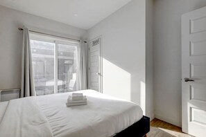 Une chambre à coucher avec un lit, une fenêtre avec des rideaux et une porte.