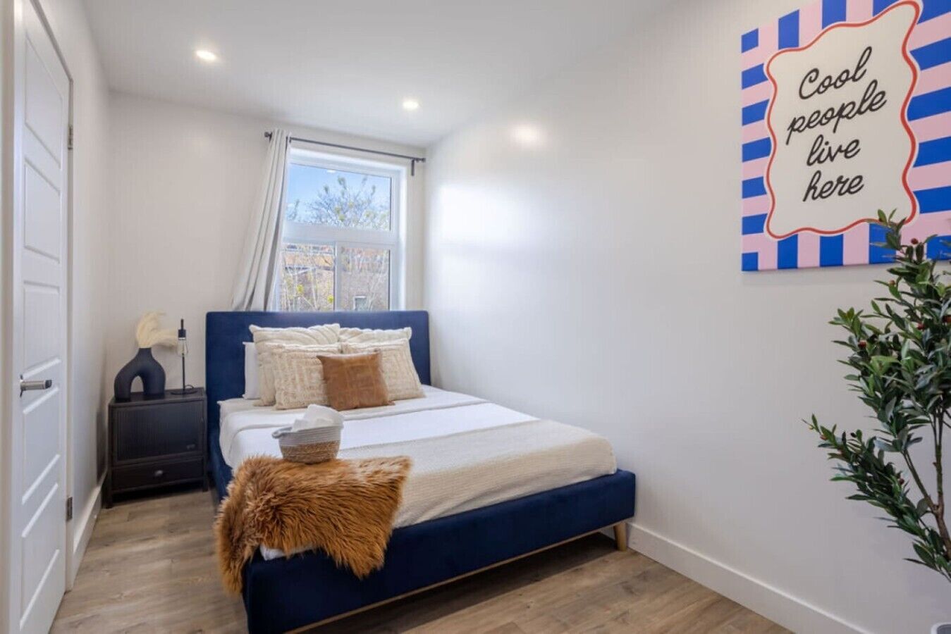 Un dormitorio con cama, mesita de noche y ventana.