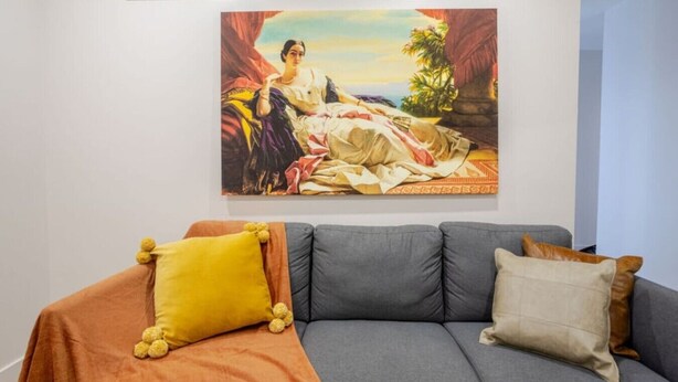 A room with a gray sofa, a yellow pillow, and a beige pillow.