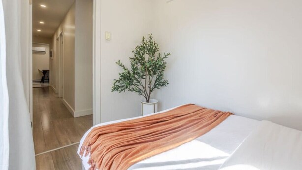 A bedroom with a bed, a potted plant, and a hallway leading to another room. - Magnificent Apartment in Montréal (Montreal)