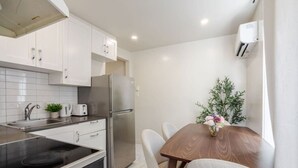 A modern kitchen with white cabinets, stainless steel appliances, a dining table with chairs, and a potted plant. - Magnificent Apartment in Montréal (Montreal)