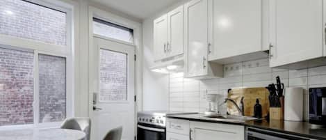 A kitchen with white cabinets, a stove, a coffee maker, and a dining table with chairs.