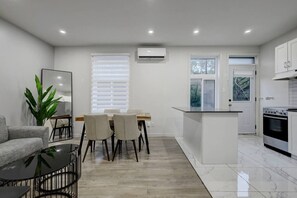 A modern kitchen with white cabinetry, a dining area with a table and chairs, and a living space with a sofa and a coffee table. - Stylish Stay in Montréal (Montreal)