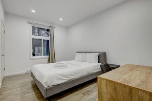 A bedroom with a bed, a window with curtains, a wooden table, and a view of a building outside. - Stylish Stay in Montréal (Montreal)