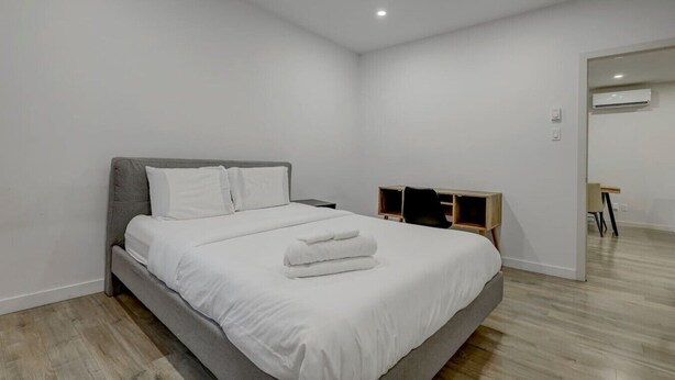 Une chambre à coucher moderne avec un lit, une table de chevet, une chaise et une armoire en bois.