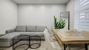 Un salon moderne avec un canapé gris, une table à manger en bois et un grand miroir.