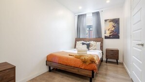 A bedroom with a wooden bed, a nightstand, a door, and a painting on the wall. - Beautiful Stay in MTL (Montreal)
