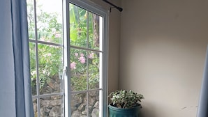 A window with a view of a garden, a potted plant on a ledge, and a staircase. - Goly's Cabin - Sky with a View of Barú Volcano (Volcán)