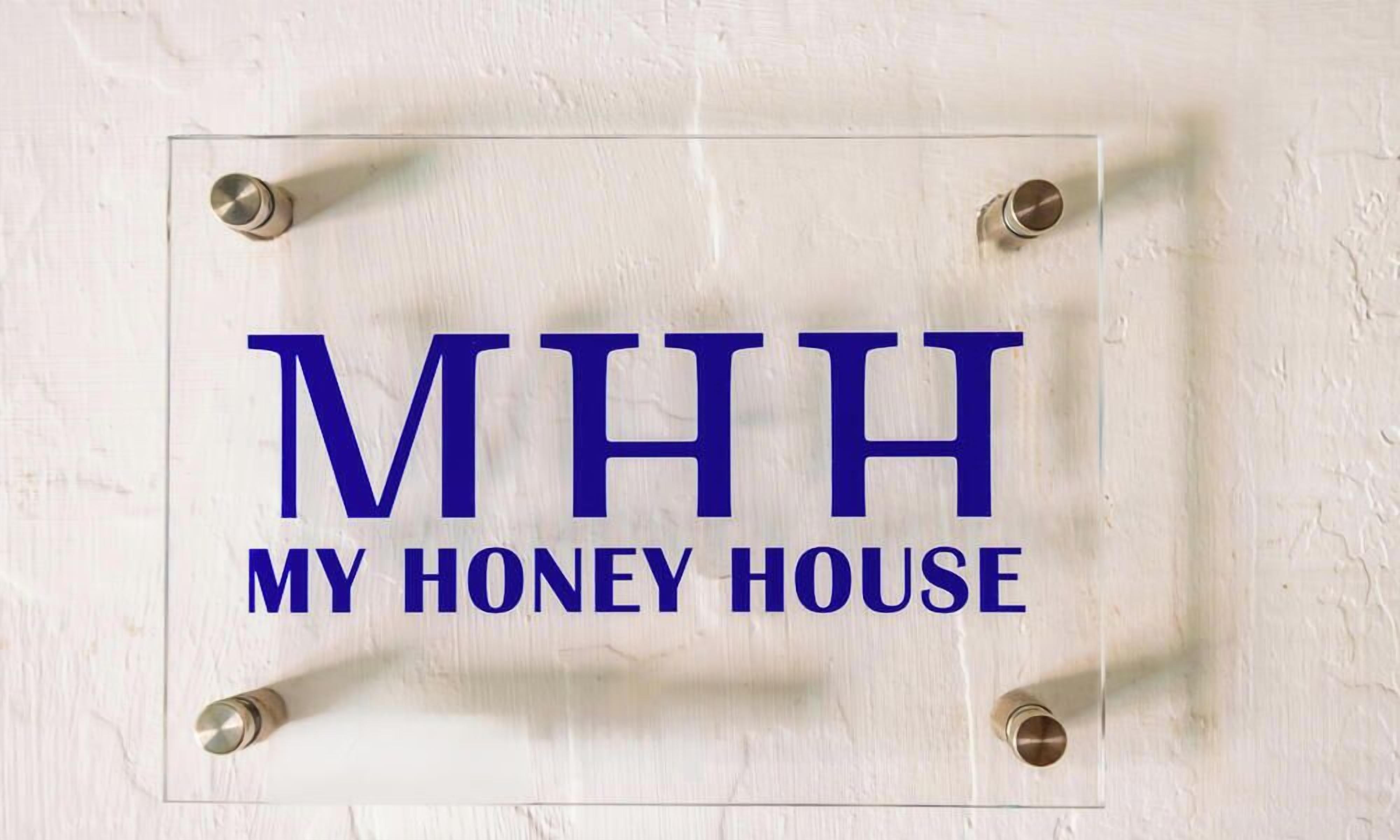 Une enseigne portant l’inscription « MHH MY HONEY HOUSE » est fixée à un mur.