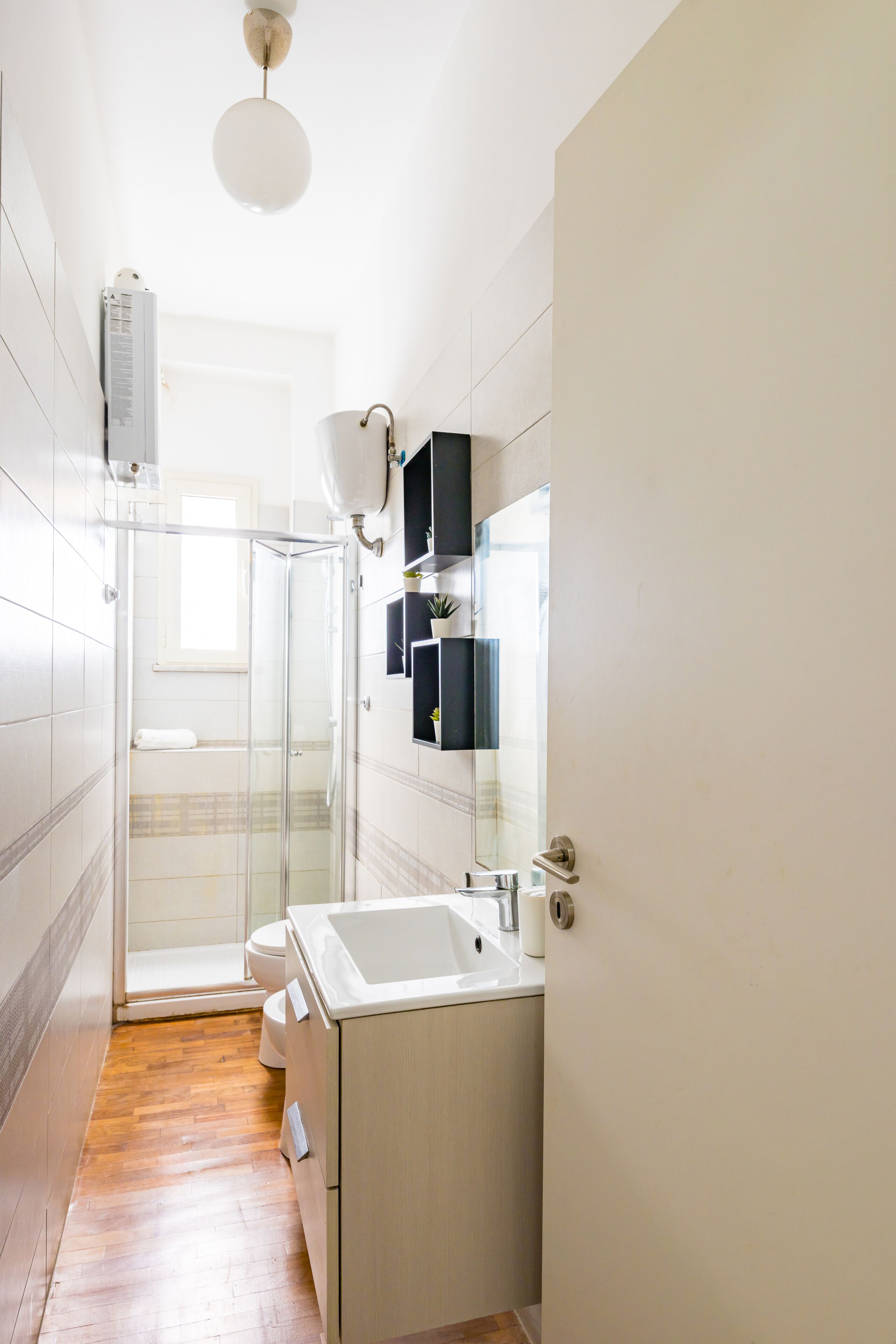 A modern bathroom with a glass shower enclosure, a white sink, and a mirror with a black frame.