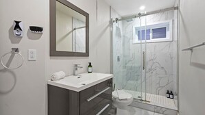 Une salle de bain moderne avec un lavabo en marbre, des toilettes et une douche à parois de verre.
