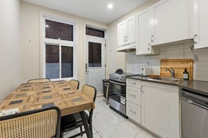 A compact kitchen with a dining table, two ovens, a sink, and white cabinets. - Perfect Stay in Montréal (Montreal)