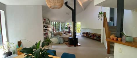 Un salon moderne doté d’une grande fenêtre, d’une cheminée et d’un coin repas avec une table et des chaises.