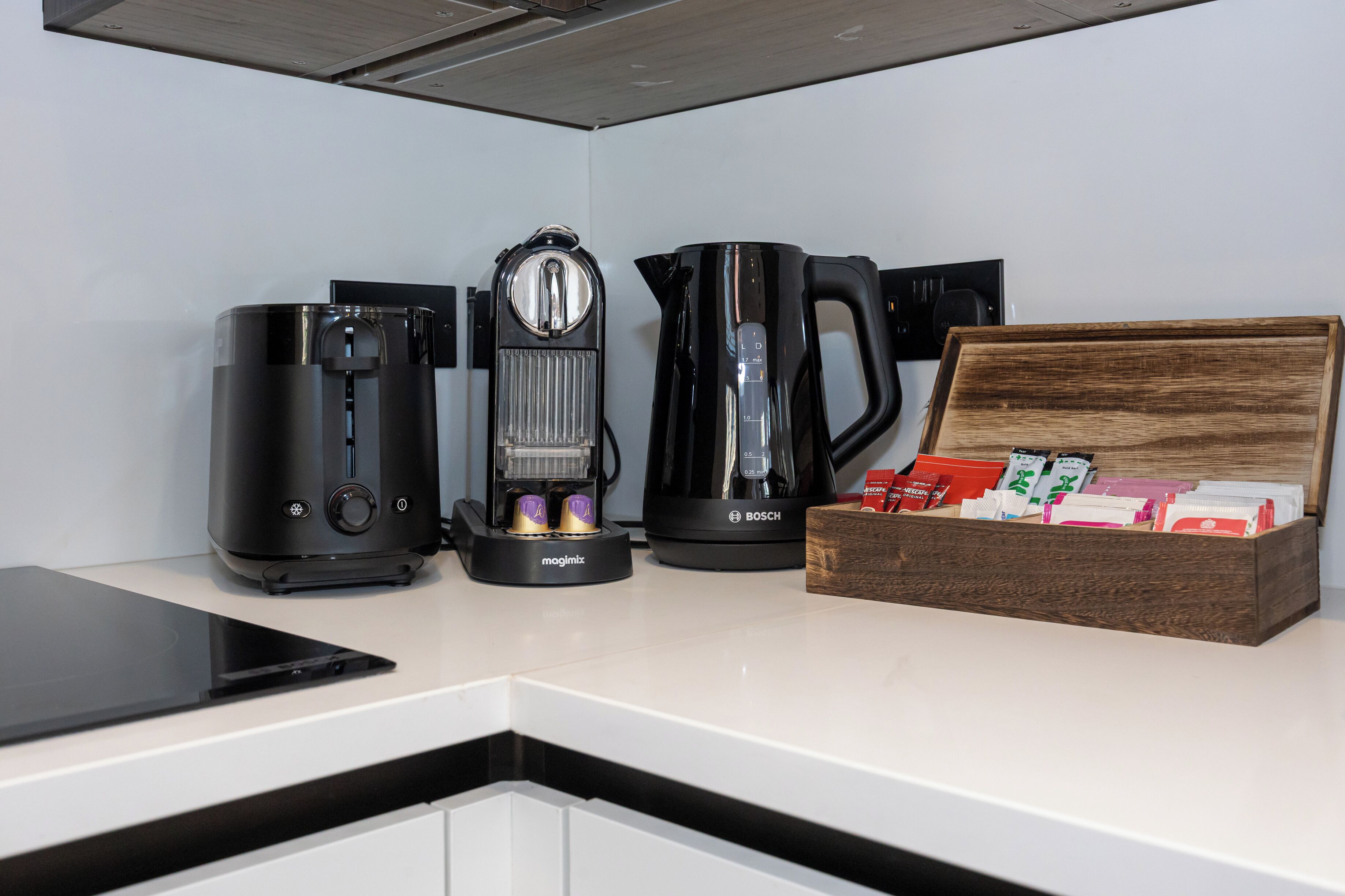 A kitchen with a coffee maker, a kettle, and a box of tea bags.