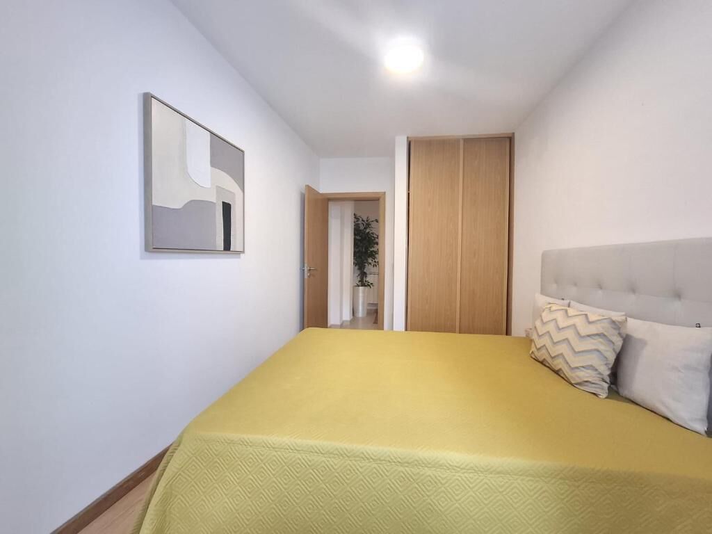 A bedroom with a bed, a headboard, a door, and a wall-mounted artwork.