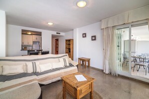A living room with a sofa, wooden coffee table, and a kitchen area visible through an open door. - LXR Marysol II 2-Bedroom. Apt (Benalmádena)