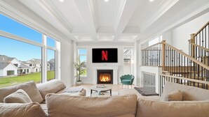 Ein Wohnzimmer mit Kamin, großem Fernseher und einer Treppe.