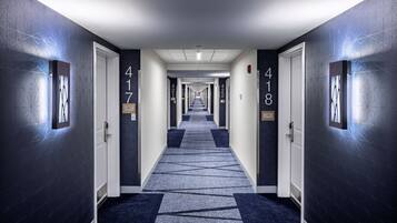 Corredor de hotel com portas numeradas 417 e 418, carpetes com padrão geométrico e paredes com design texturizado.