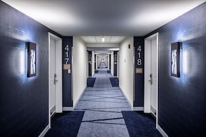 A hotel hallway with doors numbered 417 and 418, carpeted with a geometric pattern, and walls with a textured design. - Prairie Meadows Hotel (Altoona)