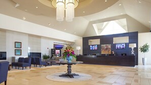 A hotel lobby with a reception desk, seating area, and a large chandelier. - Prairie Meadows Hotel (Altoona)