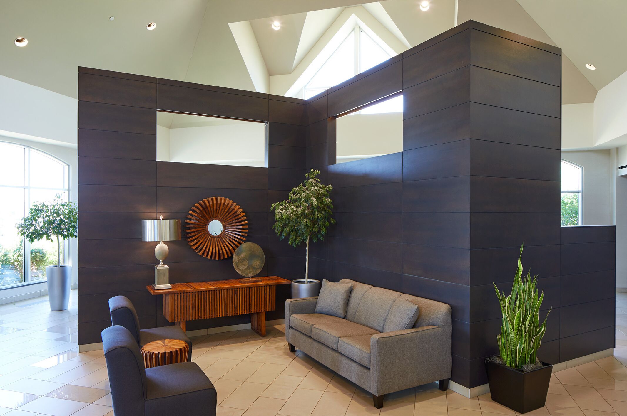 A modern living room with a sectional sofa, a wooden console table, and a large mirror.