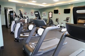 Ett gym med flera löpband, styrketräningsmaskiner och hantlar.