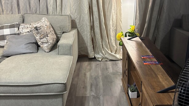 Une chambre moderne avec un canapé, un bureau en bois, une lampe et un ventilateur.