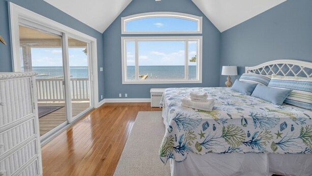 Een slaapkamer met een groot bed, uitzicht op de oceaan en een balkon.