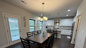 Una cocina amplia con armarios blancos, una isla central y una zona de comedor con mesa y sillas de madera.