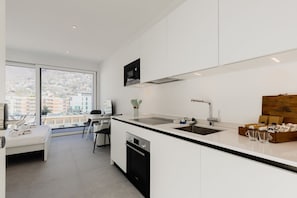 A modern kitchen with a large window, a dining area, and a bed. - {Suite 609} Gym, Business Room, Modern, Relax (Lugano)